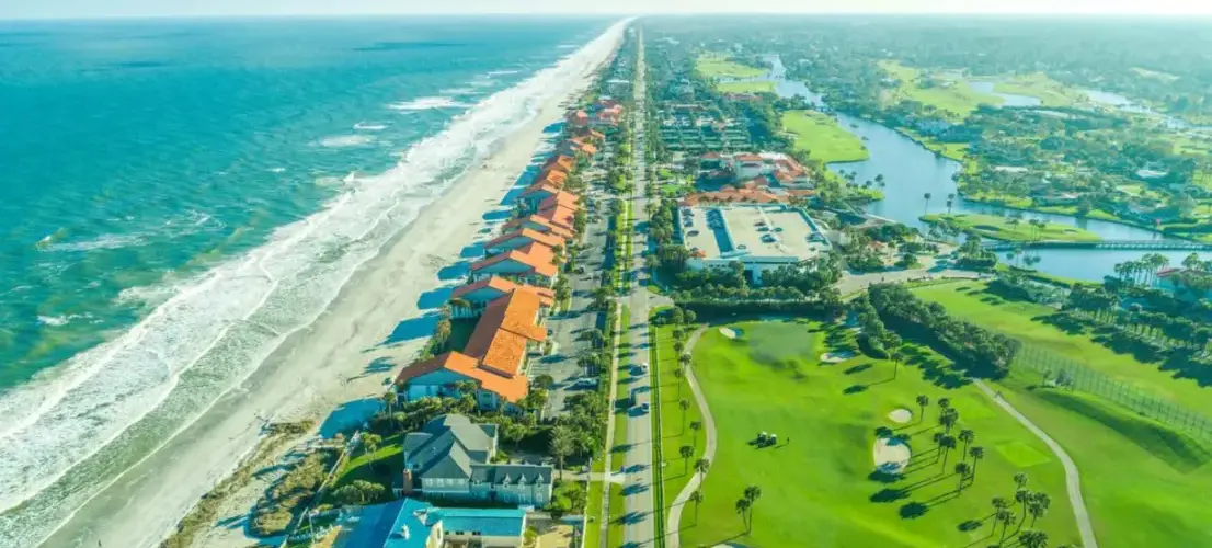 A bird’s-eye view of Ponte Vedra Beach in Jacksonville, FL, featuring the ocean, a golf course, forests, and a river.