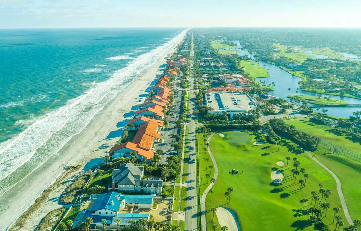 A bird’s-eye view of Ponte Vedra Beach in Jacksonville, FL, featuring the ocean, a golf course, forests, and a river.