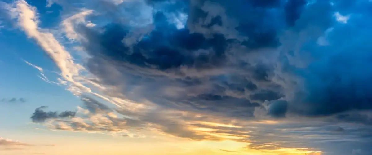 Storm clouds looming over a sailboat at sea.