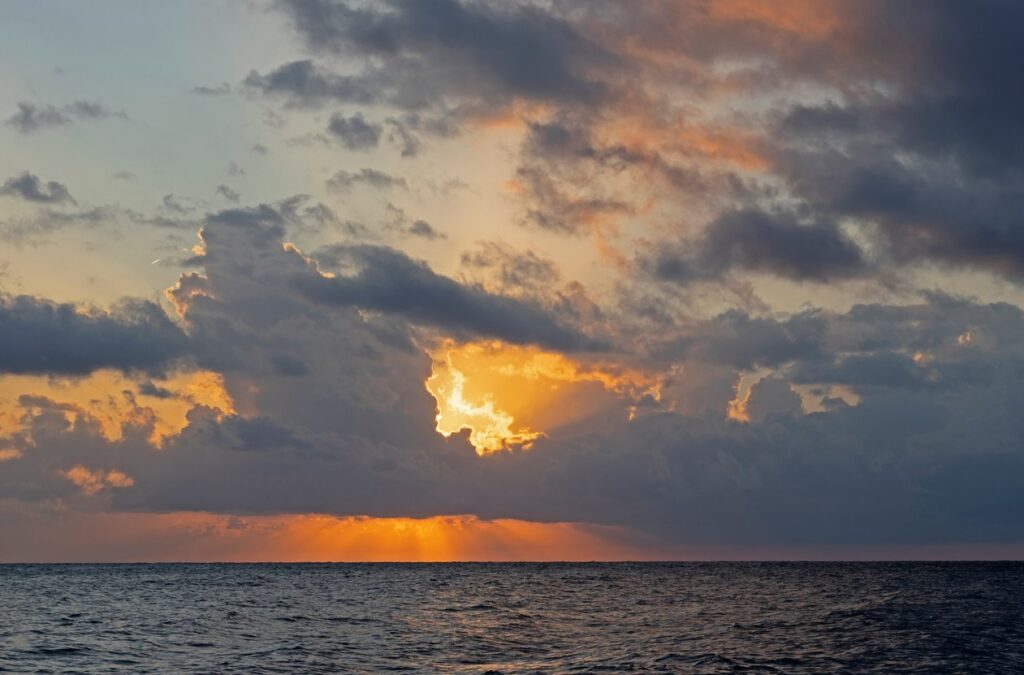 Dark clouds gather in a dusk-lit sky over the sea.