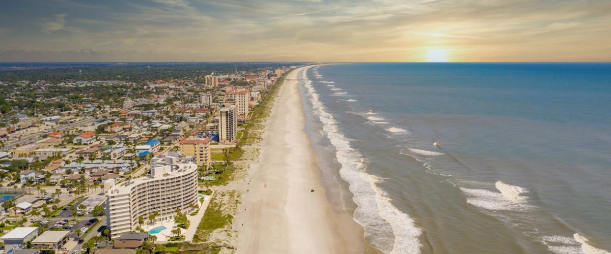 The Jacksonville Beach at sunset with hotels and homes on the left.