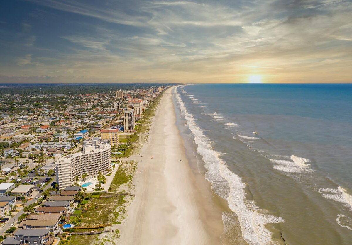 The Jacksonville Beach at sunset with hotels and homes on the left.