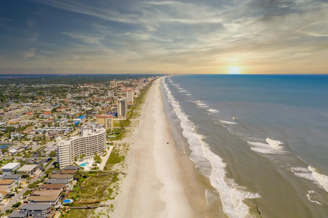 The Jacksonville Beach at sunset with hotels and homes on the left.