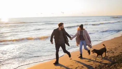Couple at the beach in the winter with their dog.