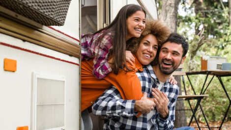 A family enjoying time together outside their RV during a camping trip, smiling and looking out the door.