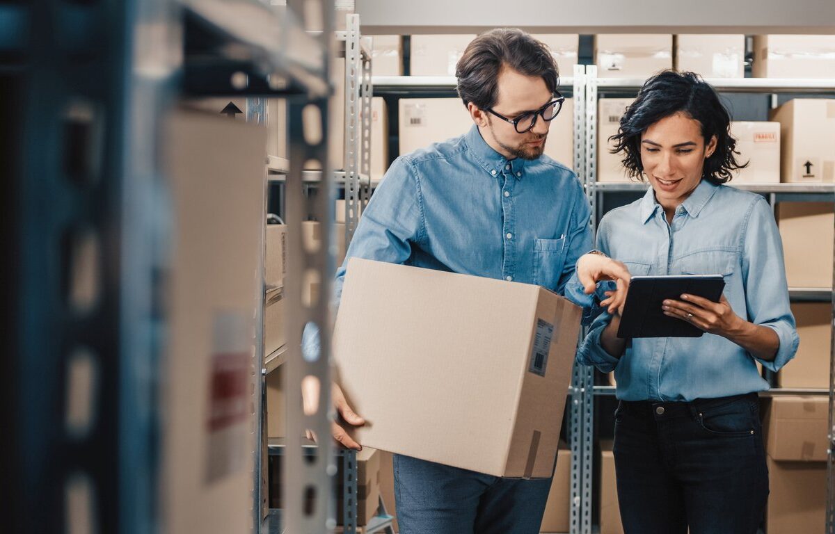 Inventory Manager Shows Digital Tablet Information to a Worker Holding Cardboard Box