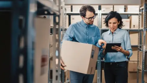 Inventory Manager Shows Digital Tablet Information to a Worker Holding Cardboard Box