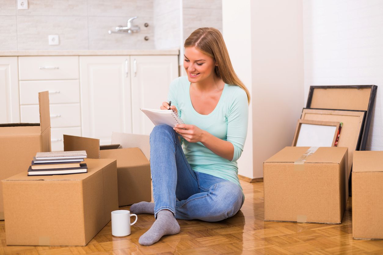 A woman writing notes while unpacking in her new home.